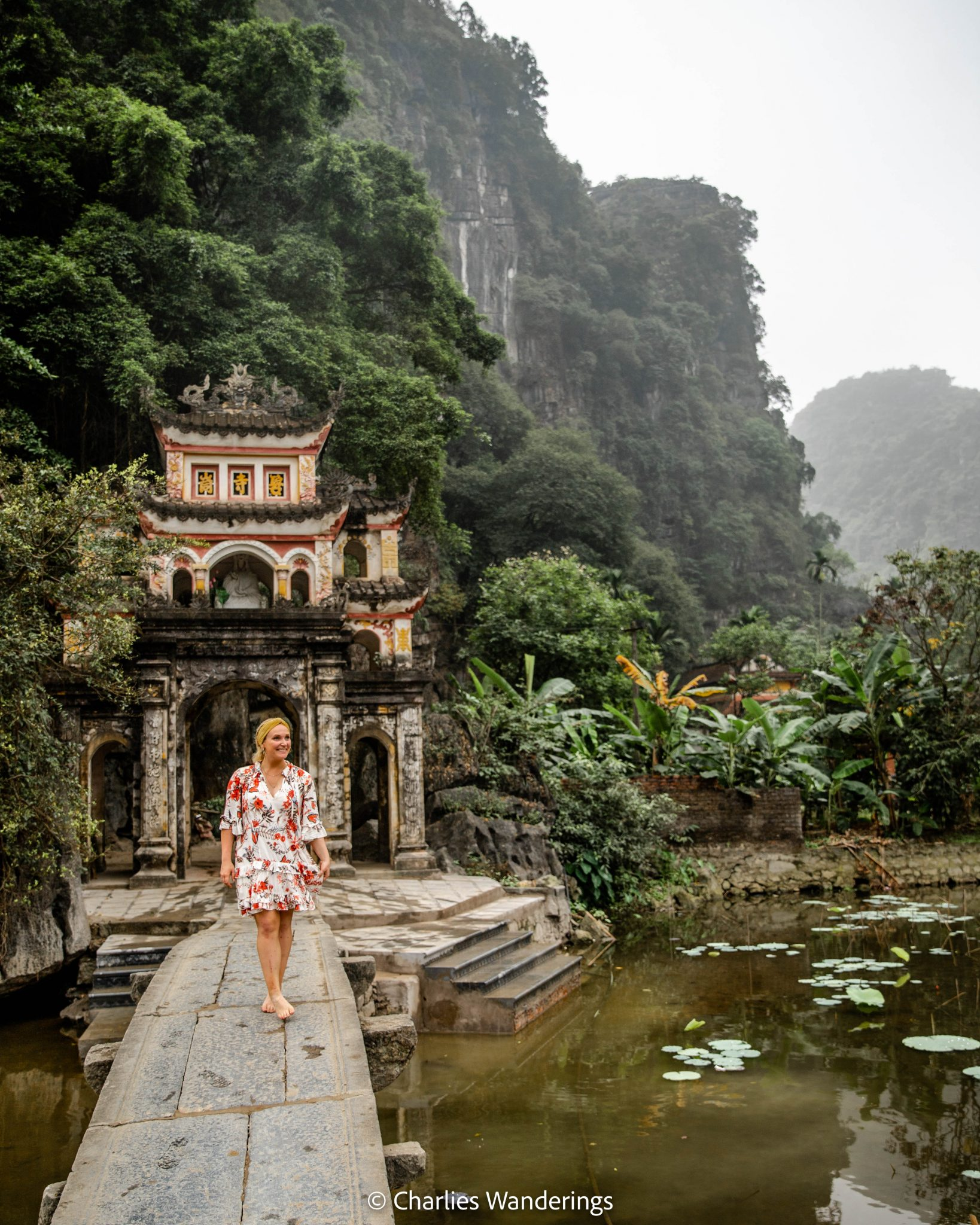 Woman on stone bridge at a Vietnamese temple gate
